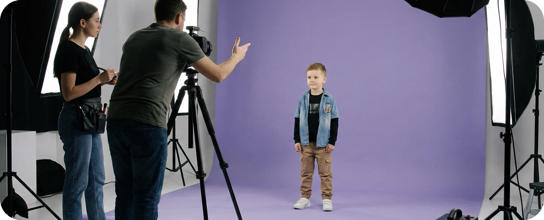 Scena z planu zdjęciowego: mężczyzna instruuje młodego modela, w tle widać wizażystkę przygotowującą się do pracy w studio.